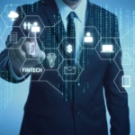 Enterprise Disaster Recovery Planning. A man in a business suit interacts with a transparent screen showing various technology icons. The display includes symbols for fintech, cloud, identity management, money, data analytics, and security—conveying themes of digital finance and secure systems.