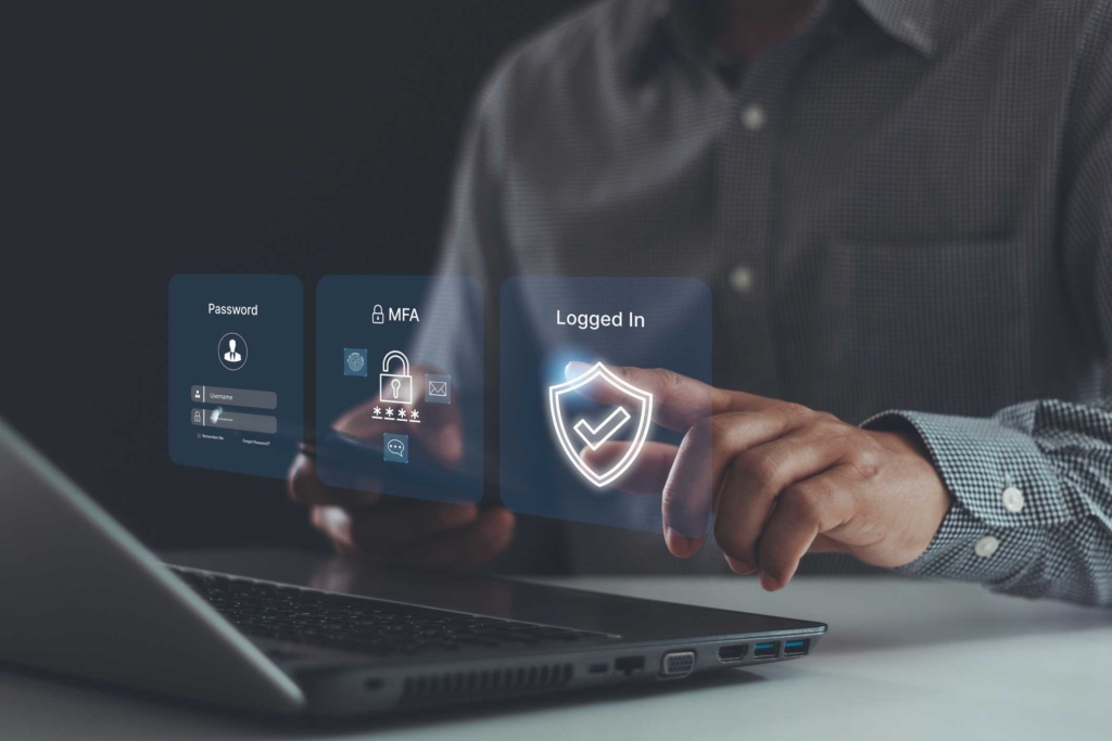 Patch management for ransomware defense. This image shows someone interacting with a holographic interface emerging from a laptop. They touch virtual screens displaying icons indicating password entry, multi-factor authentication (MFA), and a shield icon confirming successful login. The person is in professional attire, reinforcing the concept of secure digital identity verification and cybersecurity.
