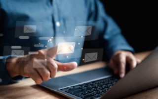 Cyber Threat Education for Staff. The image shows a person interacting with floating email icons on a screen, suggesting email communication or security in a professional setting.