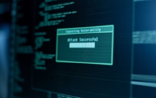 Email Security for Small Businesses. A blurry computer monitor displays green text indicating a vulnerability has been exploited, with the phrase “Attack Successful” prominently shown. The background contains code and script-like lines, symbolizing a breach or cyberattack.