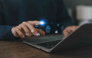 Insider Threat Training Programs. A person uses a finger to interact with a laptop. Floating icons above the hand depict cloud storage, a fingerprint scan, government buildings, and other digital services. It suggests secure access, cloud computing, and digital identity verification.