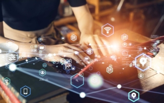 Ransomware incident reporting system. Hands type on a laptop in a warmly lit environment while a burst of glowing digital icons—representing Wi-Fi, search, security, and mobile apps—float above the keyboard, evoking the idea of digital transformation and connectivity.