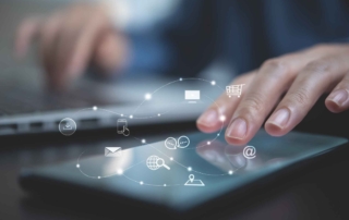 Next-Gen Antivirus Tools. A person is interacting with a touchscreen tablet, gently tapping it with their index finger. The scene is close-up and softly lit, with a blurred laptop in the background. Overlaid on the image are glowing white icons representing various digital tools and services: an envelope (email), a shopping cart, a globe, a location pin, a folder, and a mobile device. These icons are connected by dotted lines forming a network or cloud, symbolizing cloud computing, digital workflows, or interconnected systems.