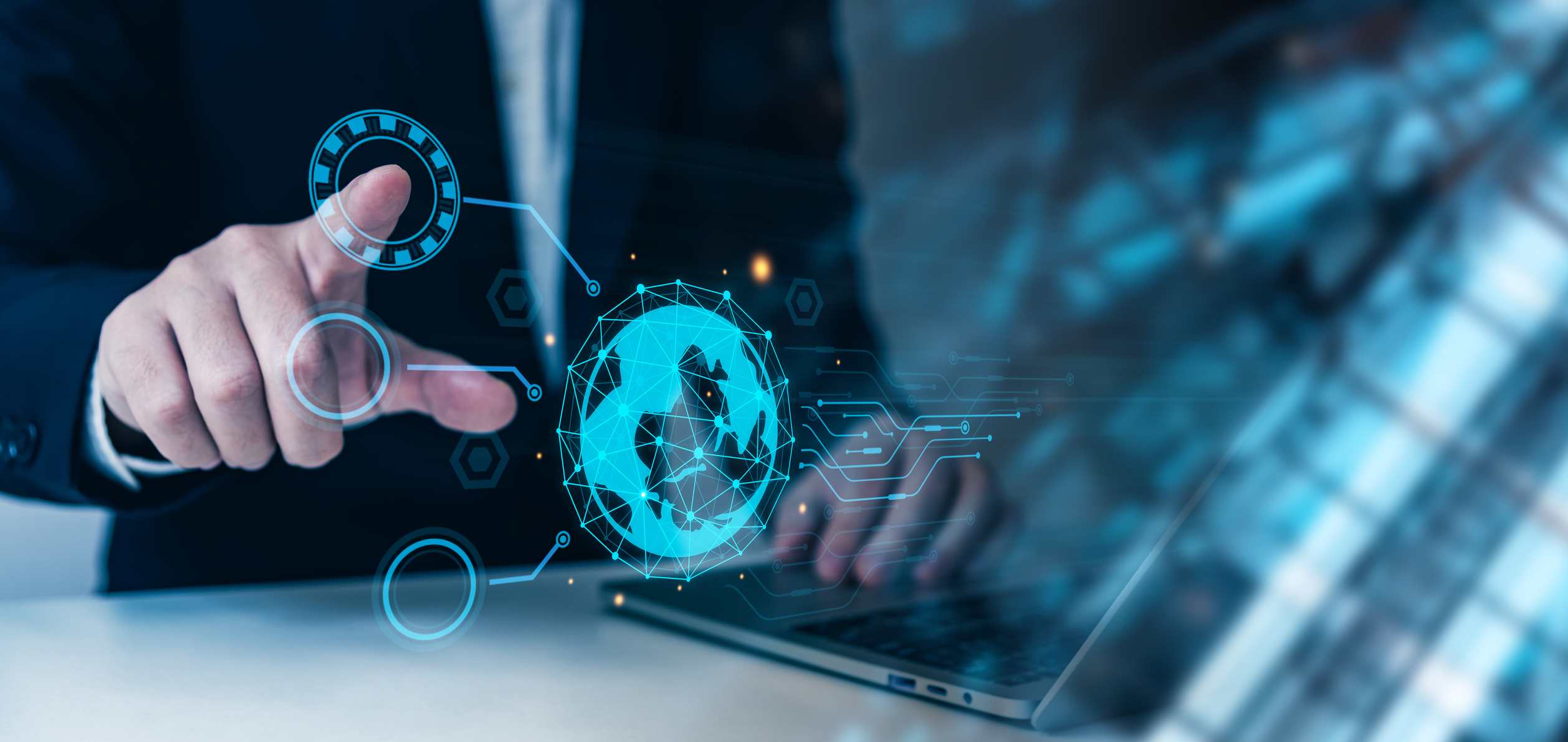 Ransomware-as-a-Service Insights. A person in a business suit points at a glowing holographic globe, with other transparent icons and lines radiating from it, positioned over a laptop keyboard.
