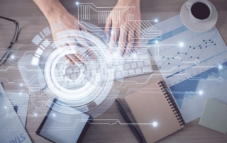 Ransomware recovery communication protocol. A top-down shot of someone typing on a white keyboard surrounded by notebooks, papers, a coffee cup, and eyeglasses. A translucent circular HUD (heads-up display) graphic overlays the scene, symbolizing data entry or secure documentation.