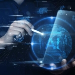 VDI ransomware security. A hand holding a stylus interacts with a glowing digital sphere representing Earth, surrounded by blue holographic icons and the large letters “AI.” The background shows faint futuristic graphics.