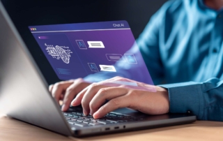Log Management in Security. A person typing on a laptop. The laptop screen displays an artificial intelligence interface in purple and blue hues with icons labeled “AI,” text boxes, and a brain graphic, suggesting interaction with an AI chatbot or assistant.